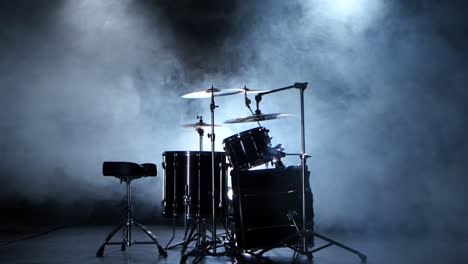 black drum set silhouette on stage with smoke