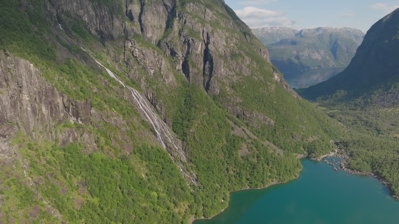 Betagende vandfald, der fosser ned ad et stejlt bjerg ned i en turkis fjord