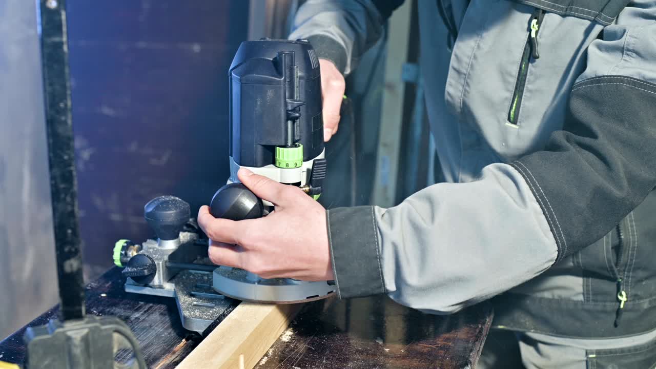 가정 작업실에서 수동 전기 절단기로 작업하는 목수의 손의 클로즈업입니다.