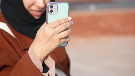 mujer en hijab tomando una selfie con un estuche de teléfono verde