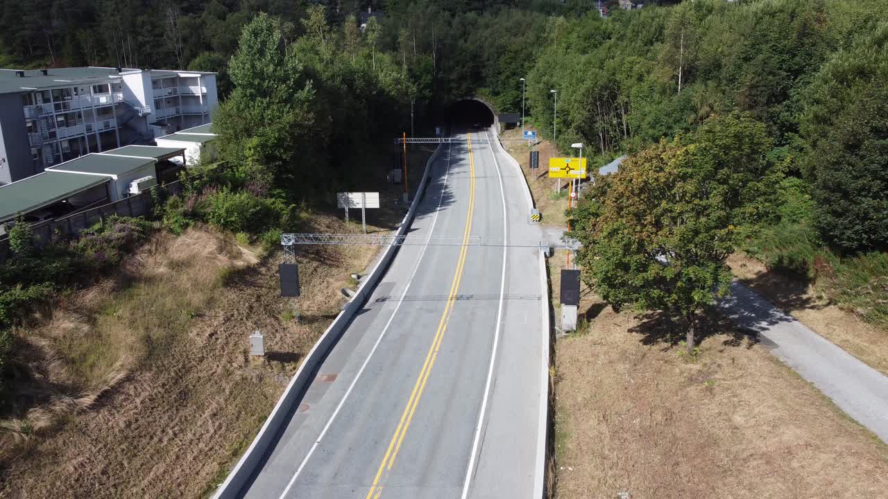 Highway E39 leading to Bergen airport Flesland and Bergen city center - Static shot above road with cars passing and driving into the Nesttun tunnel in distant