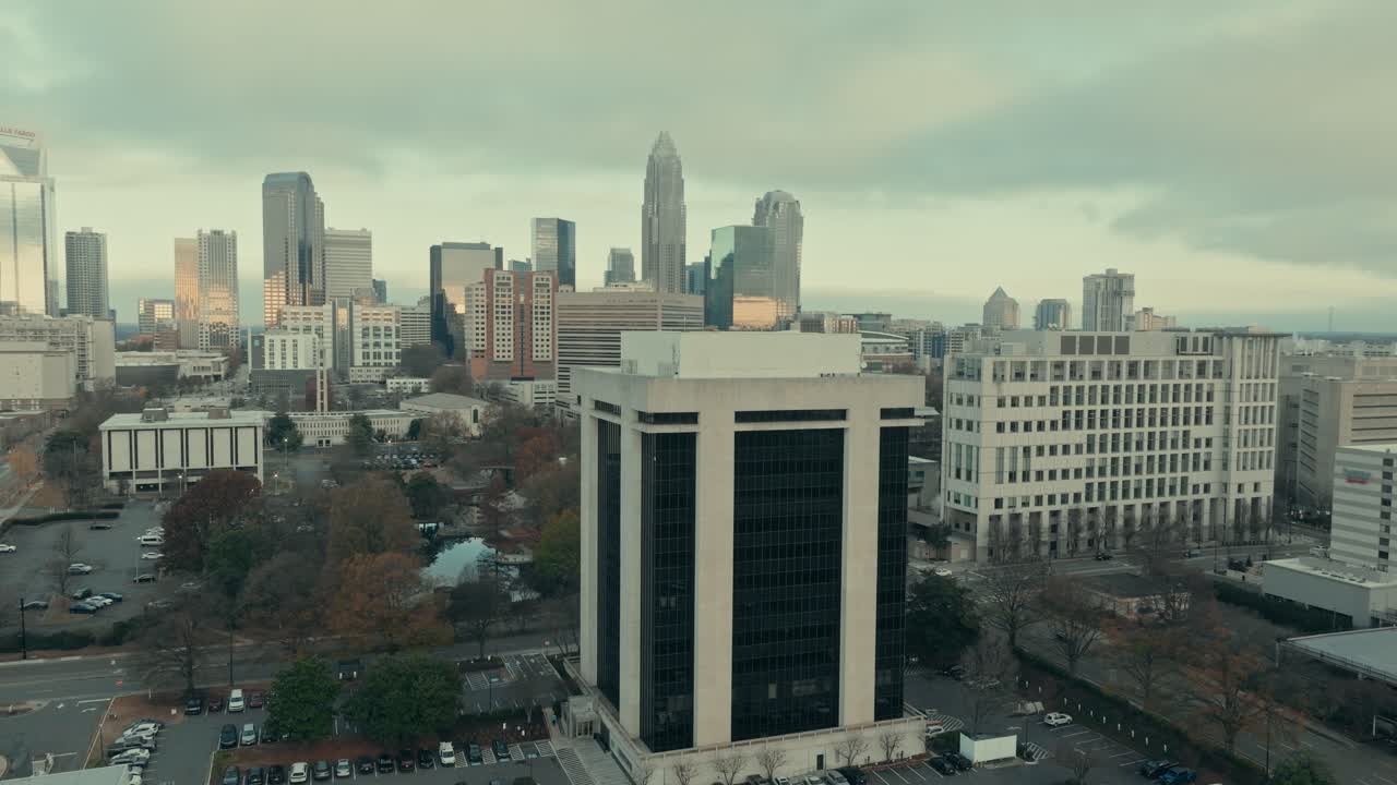 Orbita aerea in parallasse attorno all'edificio per uffici di 13 piani 301 Midtown su South McDowell Street, che rivela l'intero skyline di Charlotte, Carolina del Nord, sotto un cielo cupo e coperto.
