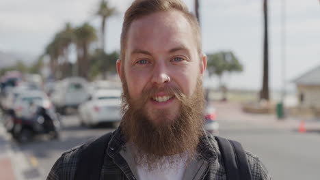 portrait of bearded hipster man smiling cheerful looking at camera enjoying summer lifestyle vacation in sunny urban city beachfront