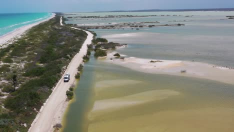 van class b driving off road with caribbean ocean and salt lake view. mexico, rio lagartos, panoramic drone shot