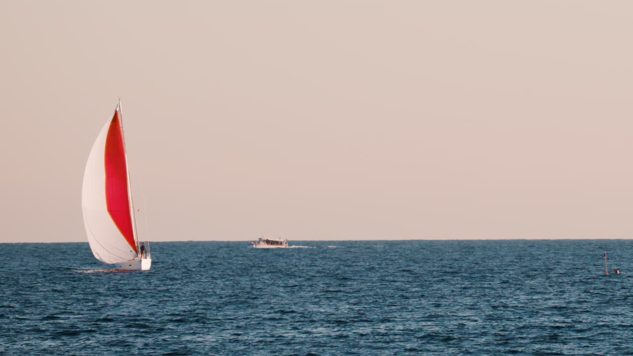 Small ship with a red sails moving on the sea in Golfe-Juan, France