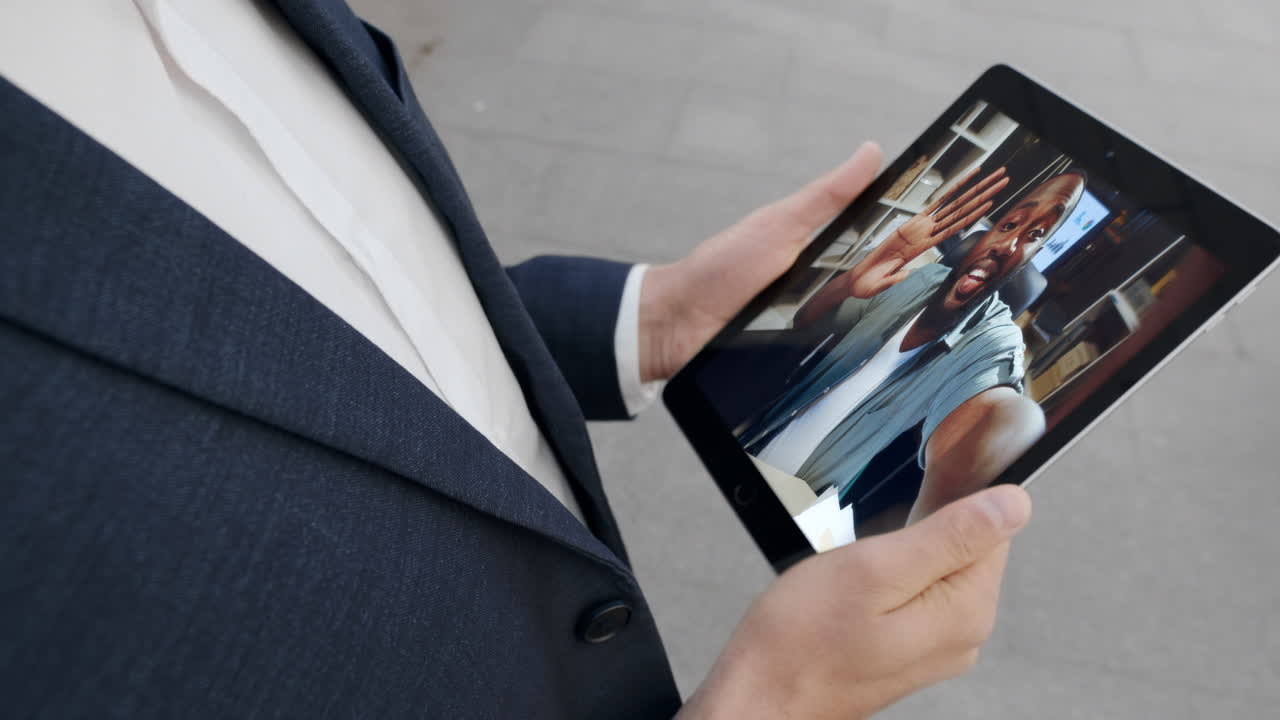 Remote worker video call to business partner holding tablet at street close up