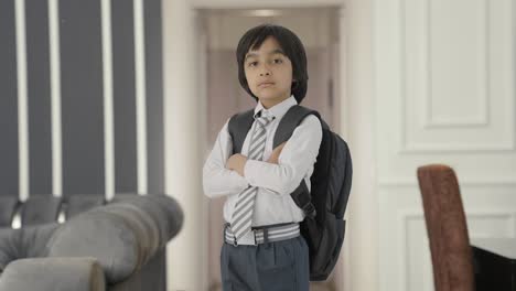 retrato de un niño de escuela indio confiado de pie con las manos cruzadas