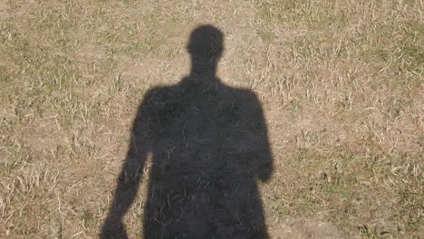 Shadow-human-walking-in-slow-motion-on-the-dry-grass,-dryness-summer-in-Europe-by-climat-change