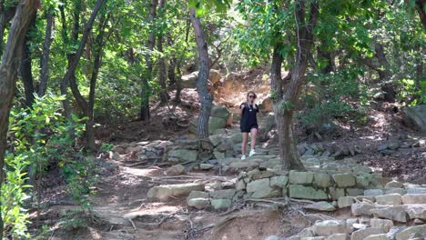 joven turista baja escalones rocosos en las montañas gwanaksan después de caminar a la cumbre