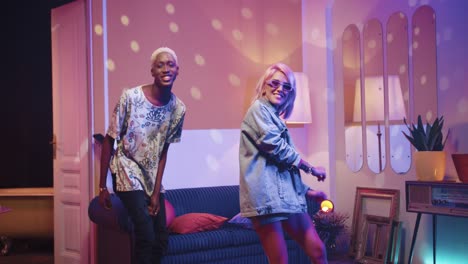 hombre afroamericano y mujer caucásica con gafas de sol bailando en una fiesta retro en casa
