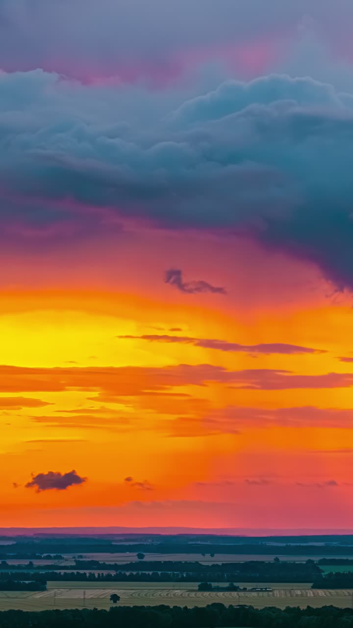 Nubes de lluvia oscuras se desplazan por un amanecer naranja en una toma aérea en time-lapse.