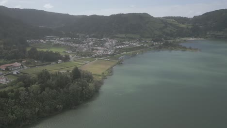 Pueblo-De-Sete-Cidades-Junto-Al-Lago-Con-Exuberantes-Colinas-Verdes-Y-Aguas-Serenas,-Vista-Aérea