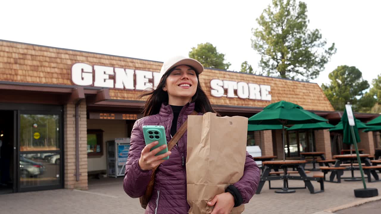 Happy Young Woman Leaving General Store with Shopping Bag and Phone