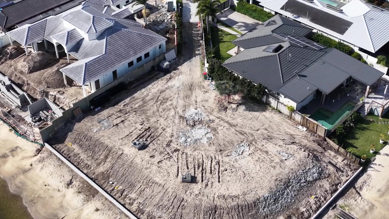 High angle drone shot reveals luxury home development on a canal front sandy lot.