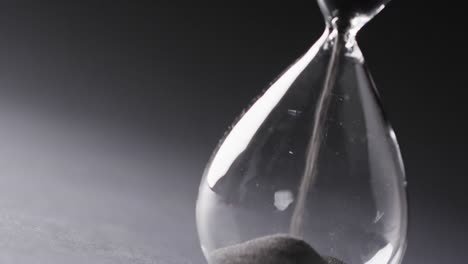 Video-of-hourglass-with-sand-pouring,-copy-space-on-black-background