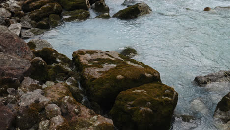 tilt up from river rocks revealing glacier river in alberta, canada