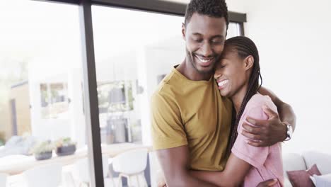 Glückliches-Afroamerikanisches-Paar-Lächelt-Und-Umarmt-Sich-Im-Wohnzimmer,-In-Zeitlupe