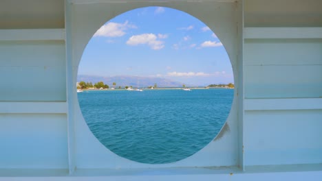 paisaje de verano de la ciudad vista de grecia vista desde el interior de una cabina de barco con ventana redonda de agujero de mirada. ventana redondeada en una pared en mal estado con marcas de cepillo y un camino de recorte de vista al mar incluido