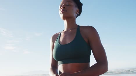 african american woman meditating at the beach on sunny day