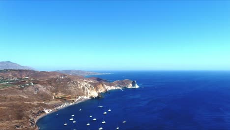 Aerial-4K-Blue-Sea-and-Sky-Top-View-of-Cliffside-with-Sailboats-Docked-in-Santorini-Greece