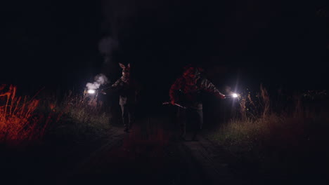 two people in rabbit masks with flashlights at night