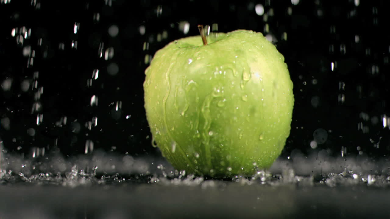 agua lloviendo sobre una manzana en súper cámara lenta