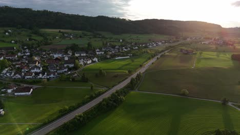 Greifensee,-switzerland,-with-lush-green-fields-and-a-serene-village-at-sunset,-aerial-view