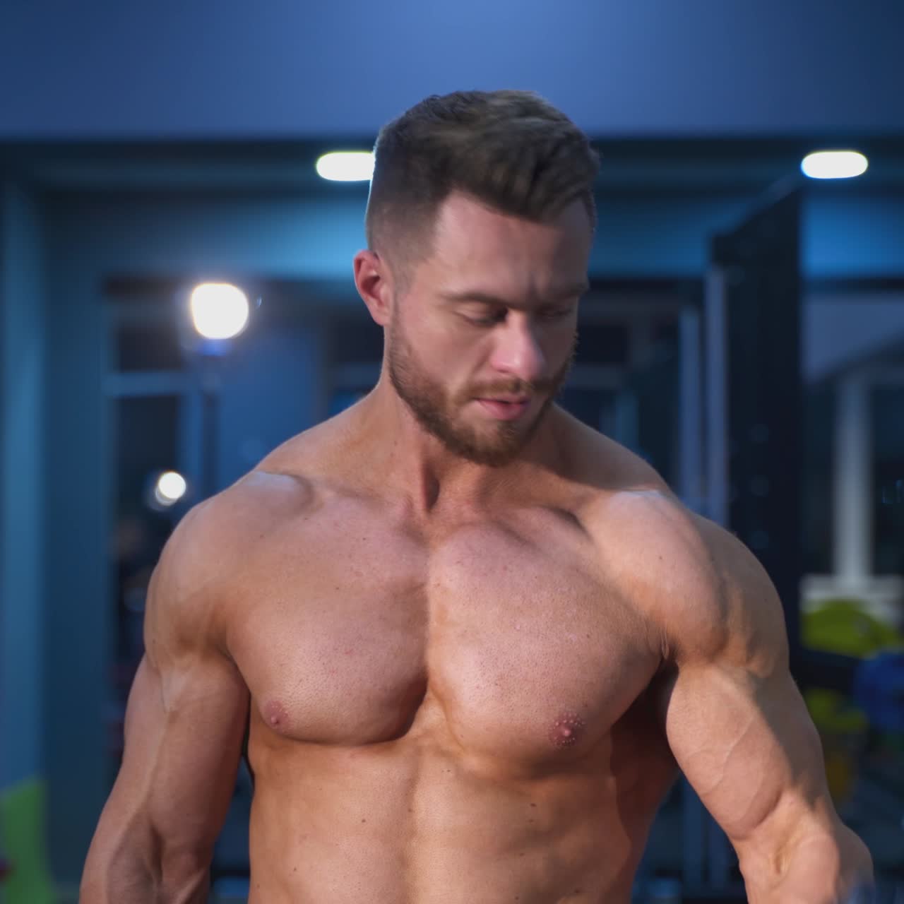 Fitness muscular man training his biceps in the gym. Handsome bodybuilder working hard at gym