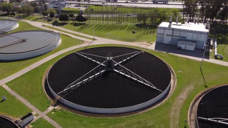 aerial orbit shot of sewage flowing through large circular tanks - filtration of water at sewage treatment plant - 4k flight