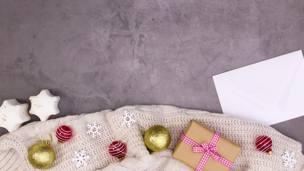 Winter sweater with gifts, ornaments and candles appear on the bottom and paper in envelope for text. Stop motion