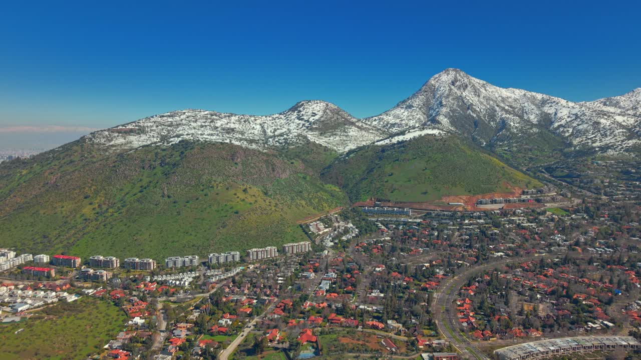 Smooth dolly shot moving forward over Santiago homes with snowy Andes mountains in view