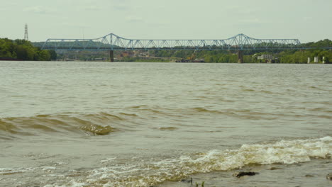 Ein-Blick-Auf-Die-Monaca-East-Rochester-Bridge-Im-Westen-Von-Pennsylvania-Mit-Den-Wellen-Des-Ohio-River,-Die-An-Der-Felsigen-Küste-Im-Vordergrund-Krachen