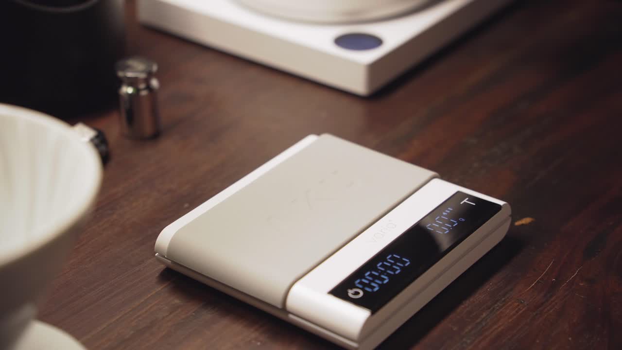Barista put ceramic cup on scales and push tare button to zero out weight