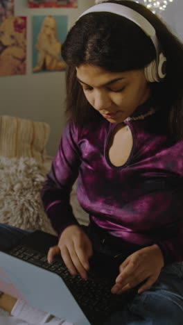 teenage girl working on laptop in bedroom