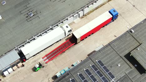 los camiones con semirremolques se paran en el estacionamiento del parque logístico con centro de carga y esperan la carga y descarga de mercancías en las rampas del almacén al atardecer