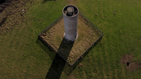 dynamic aerial pullback of a cylindrical water tower, revealing lush green surroundings, galway, ireland