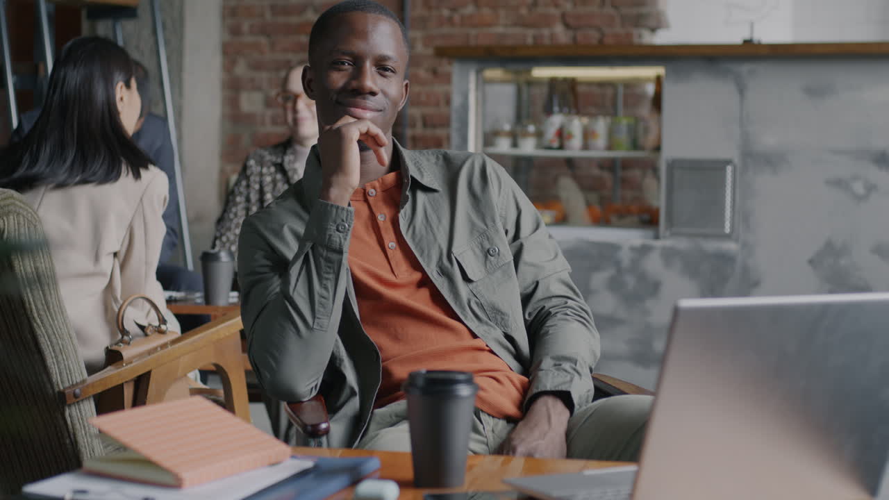 Man in a cafe, smiling, working on a laptop