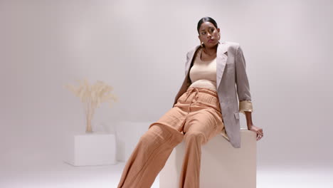 leaning forward indian woman shifting and twisting poses on white cube by dried reeds in studio
