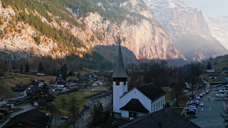 peaceful church by the river in lauterbrunnen, switzerland sits in the shade of the cliff walls above