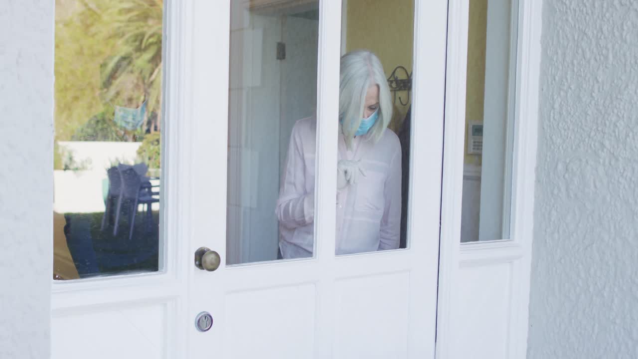 Delivery man delivering package to senior couple wearing face mask at home