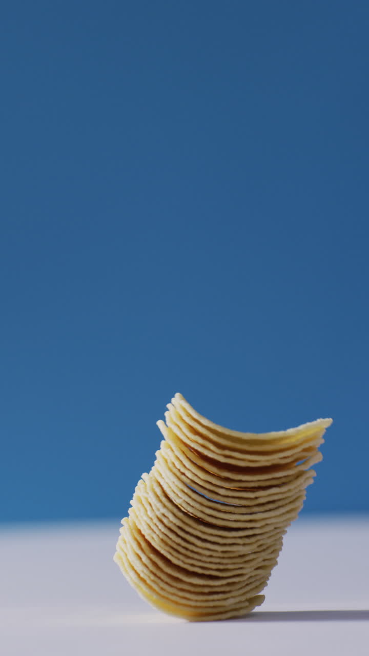 Vertical video of chips falling on white and blue background