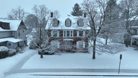 snow-dusted traditional homes and trees line a quiet residential street