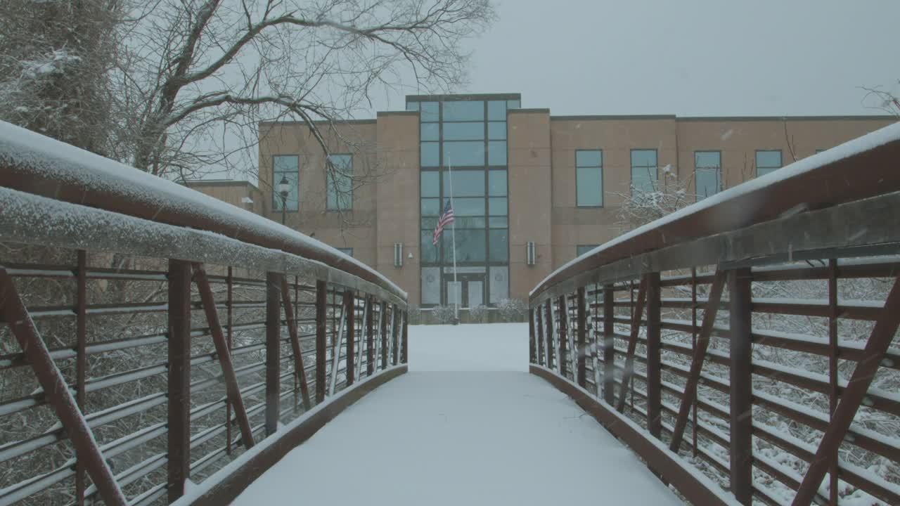 Statisk utsikt over en liten gangbro over en elv i Durango, Colorado, USA, med snø som faller på bakken på en skyet dag