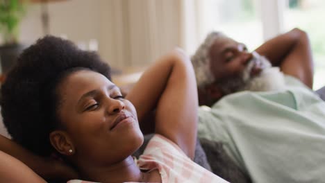 Feliz-Pareja-Afroamericana-Recostada-En-El-Sofá-Girando-Y-Sonriéndose-El-Uno-Al-Otro