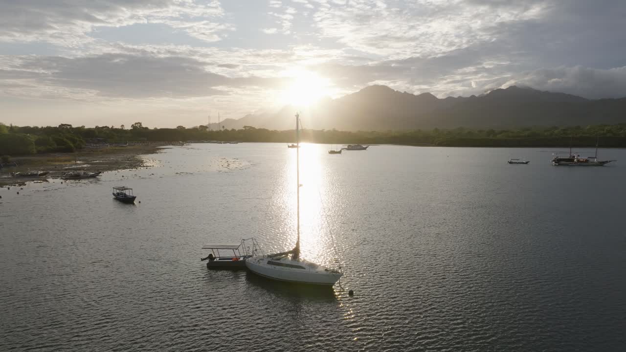 Vista con drone di barche in una baia tranquilla all'alba nel Parco Nazionale di Bali Occidentale, con montagne e costa tropicale riflesse nell'acqua, che cattura la natura serena, i viaggi e il paesaggio dell'isola.