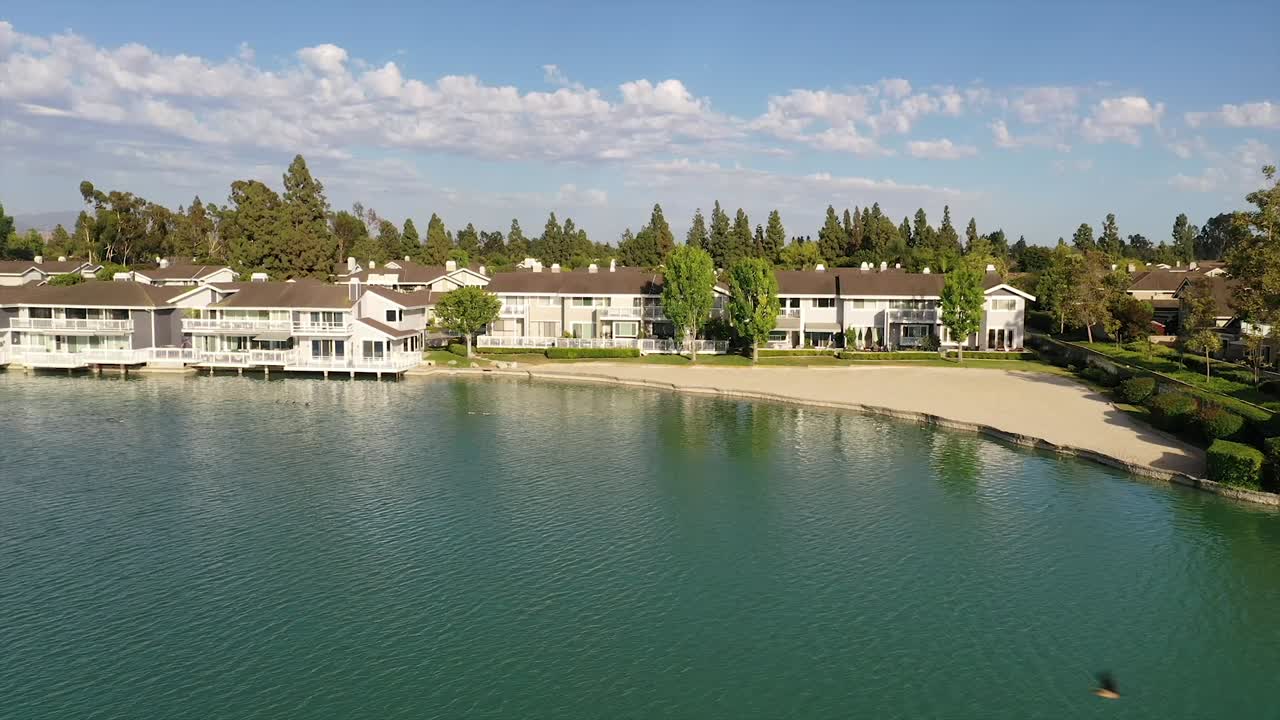 foto aérea de viviendas, apartamentos, condominios que se ciernen sobre el lago woodbridge north en irvine, california en un cálido día soleado de 2022 con hermosas nubes y cielos azules