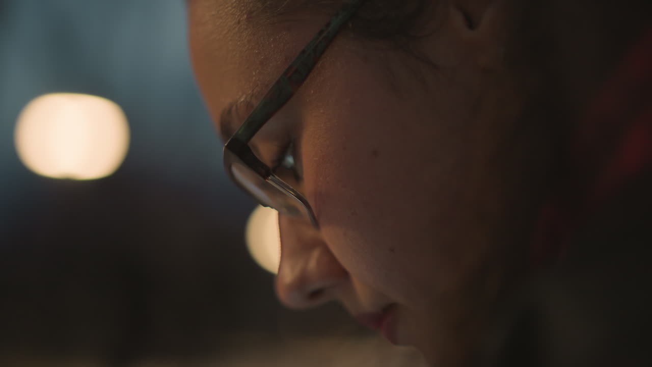 Gentle Smile Under Streetlights, Reflective Lady Communicates Softly Beneath Warm Streetlamp Illumination, Nighttime Scene Of Woman Engaged In Intimate Messaging Amid Cozy Bokeh Ambience
