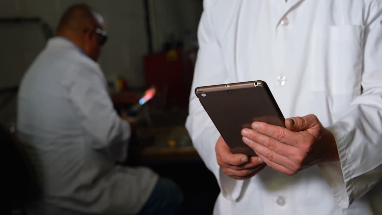 sección media de un trabajador masculino trabajando en una tableta digital en una fábrica de vidrio 4k