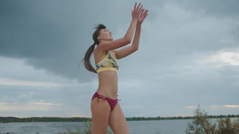 mujer deportiva está sirviendo la pelota en un partido de entrenamiento de voleibol de playa y preparándose para la competencia de tiro medio