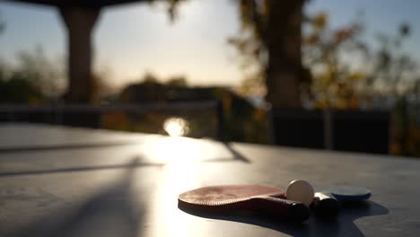 Ping-pong-table-with-paddles-located-on-a-terrace-in-Cannes-France-with-sun-shining,-Close-up-handheld-shot